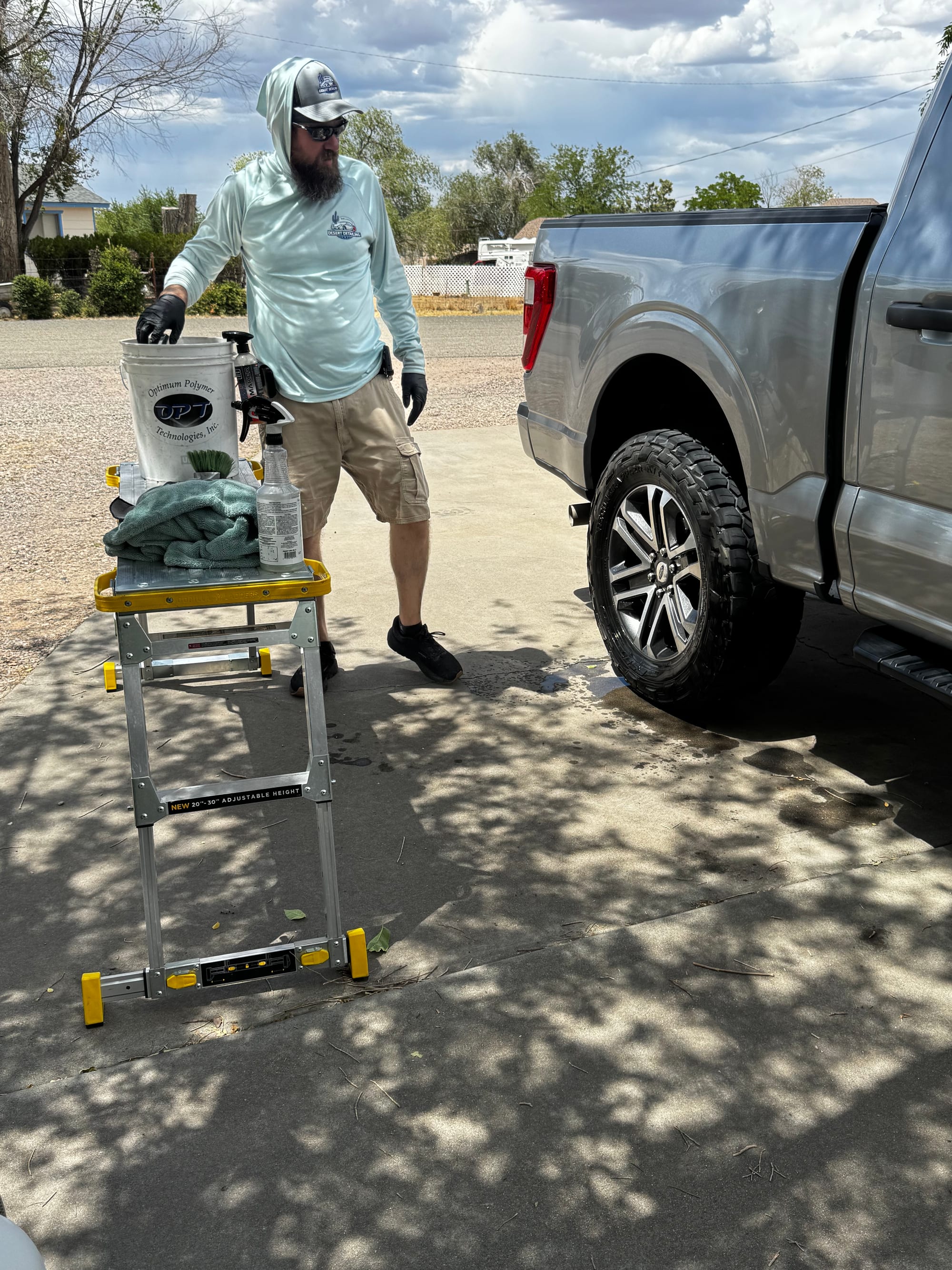 Detailer hand-washing a Ford F-150 under a dramatic Arizona sky