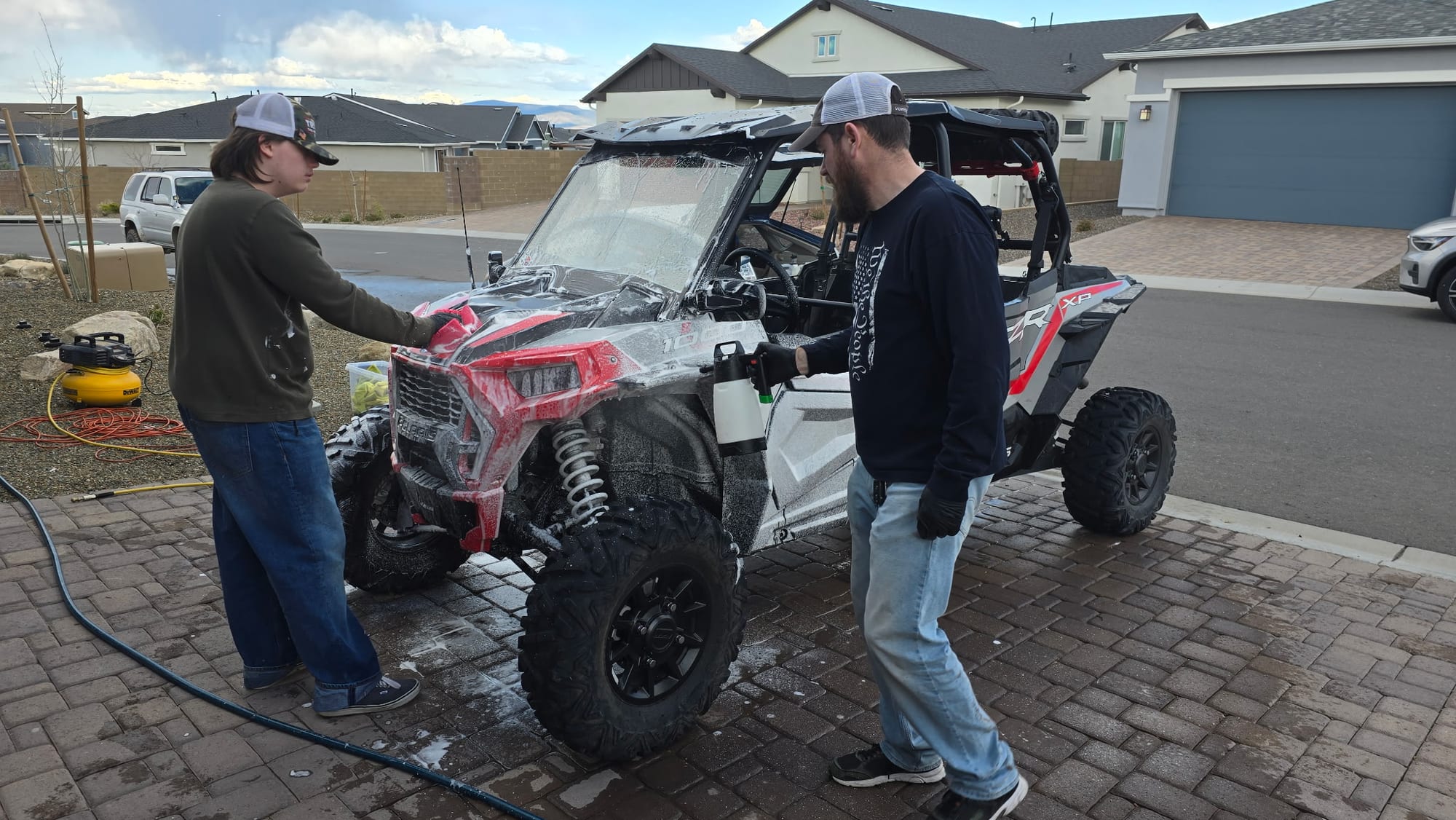 Delightful Desert Detailing team foam-washing a red Polaris RZR XP 1000 in a customer's driveway